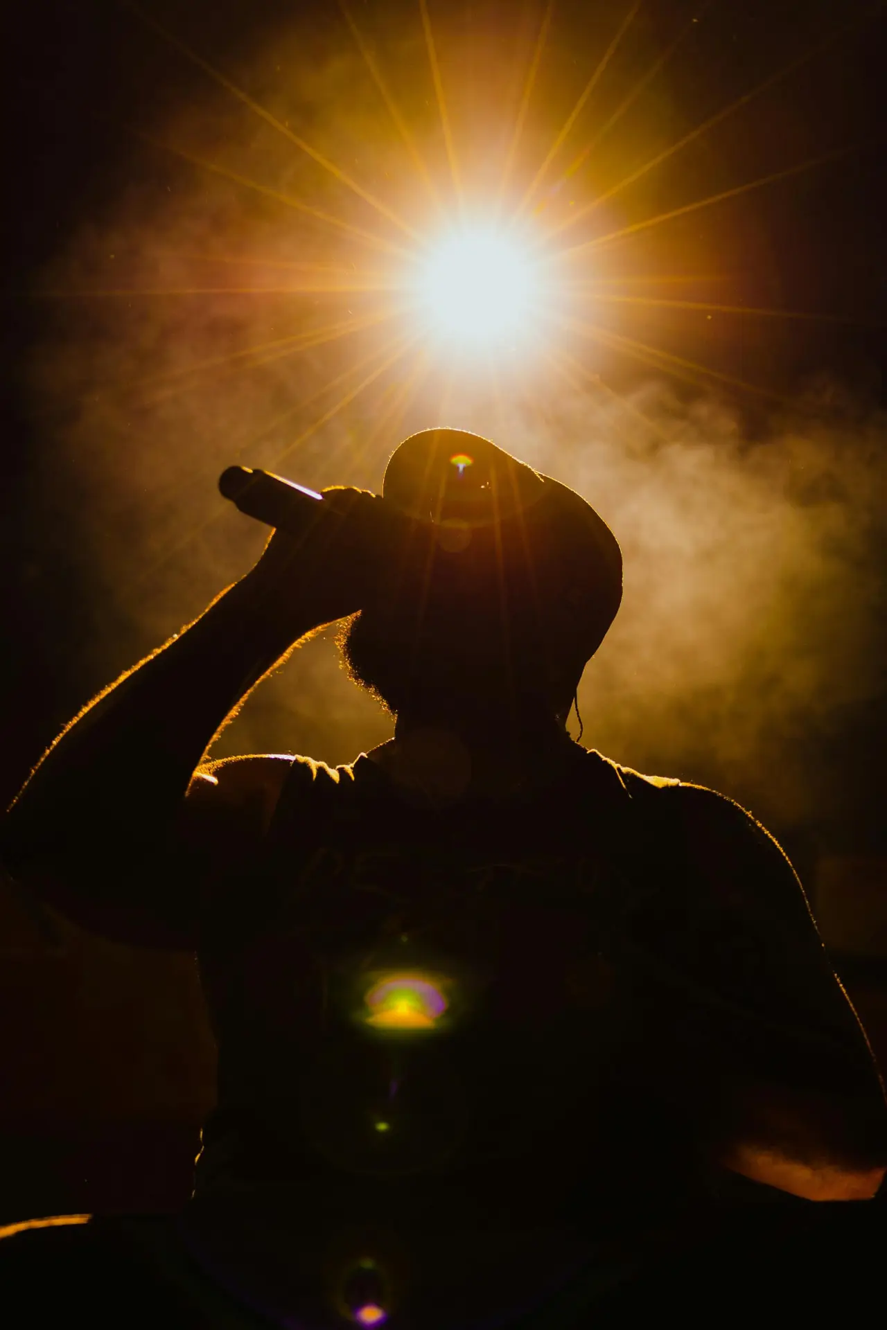 Silhouette d'un rappeur au micro dans un contre-jour doré