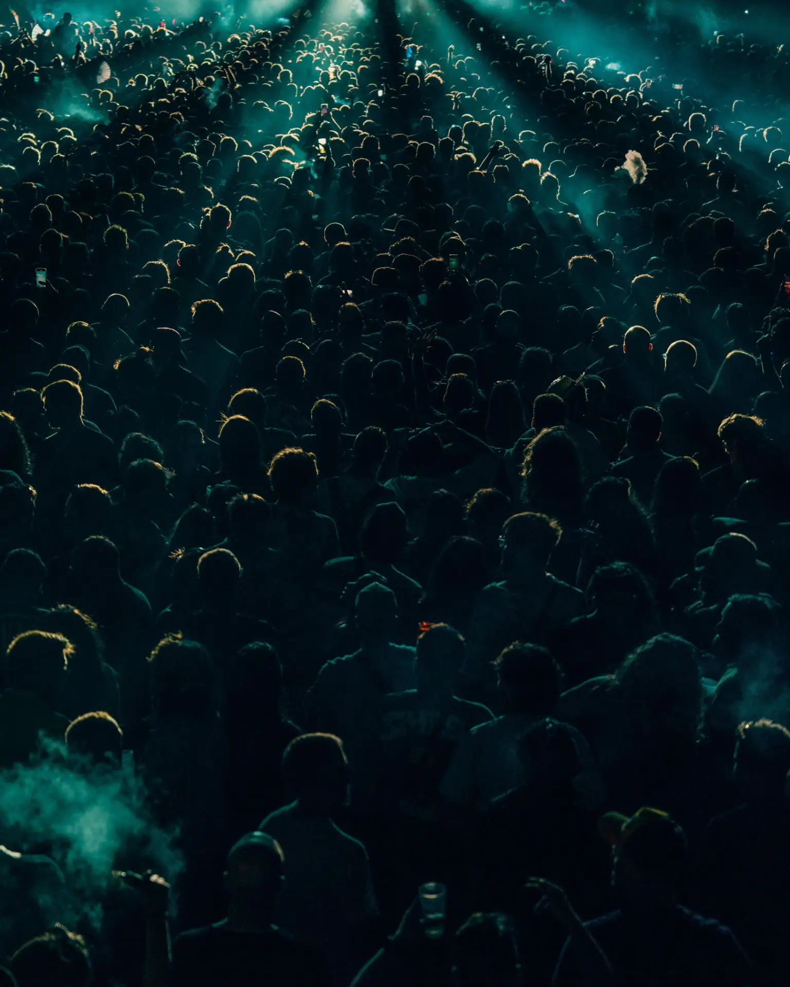 Foule immense captée en plongée sous des faisceaux turquoise